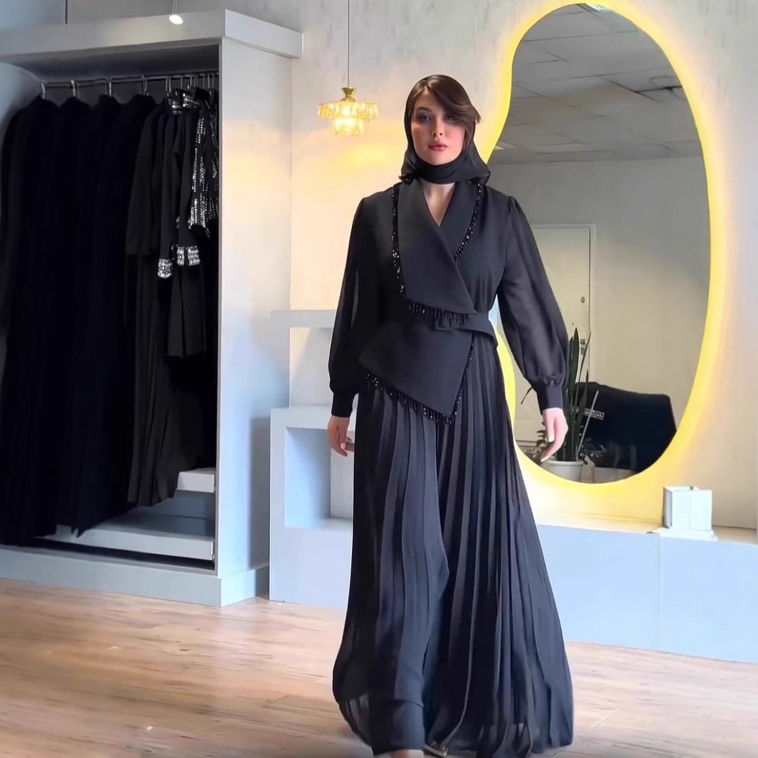 بدلة من قطعتين بلون موحد، بخياطة مطوية وياقة عريضة، مزينة بتفاصيل أنيقة.